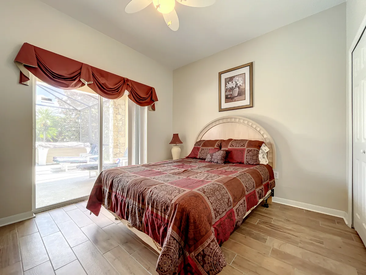 Queen bedroom with pool view through sliding patio doors