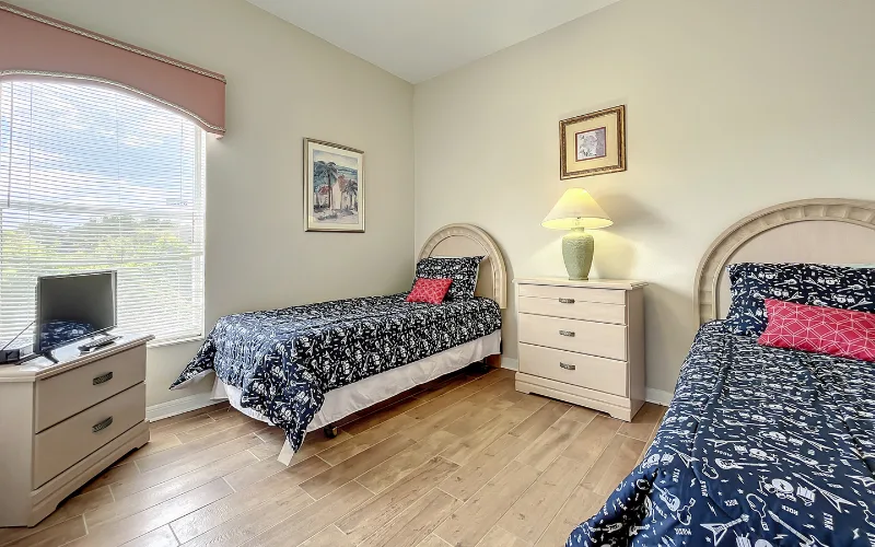Twin bedroom with arched window, two single beds and TV