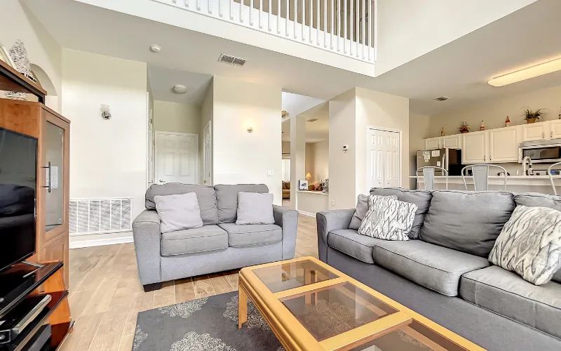 Family lounge area with grey sofas and twin sliding doors to the pool