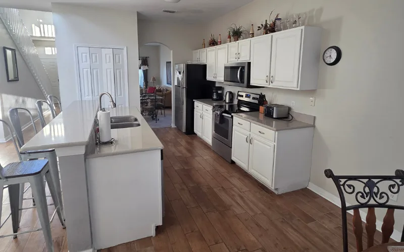 Fully equipped white kitchen with breakfast bar and stainless appliances