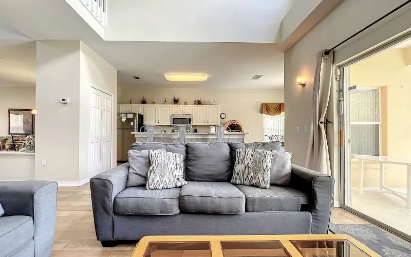 Lounge with grey sofas and high vaulted ceiling open to the kitchen