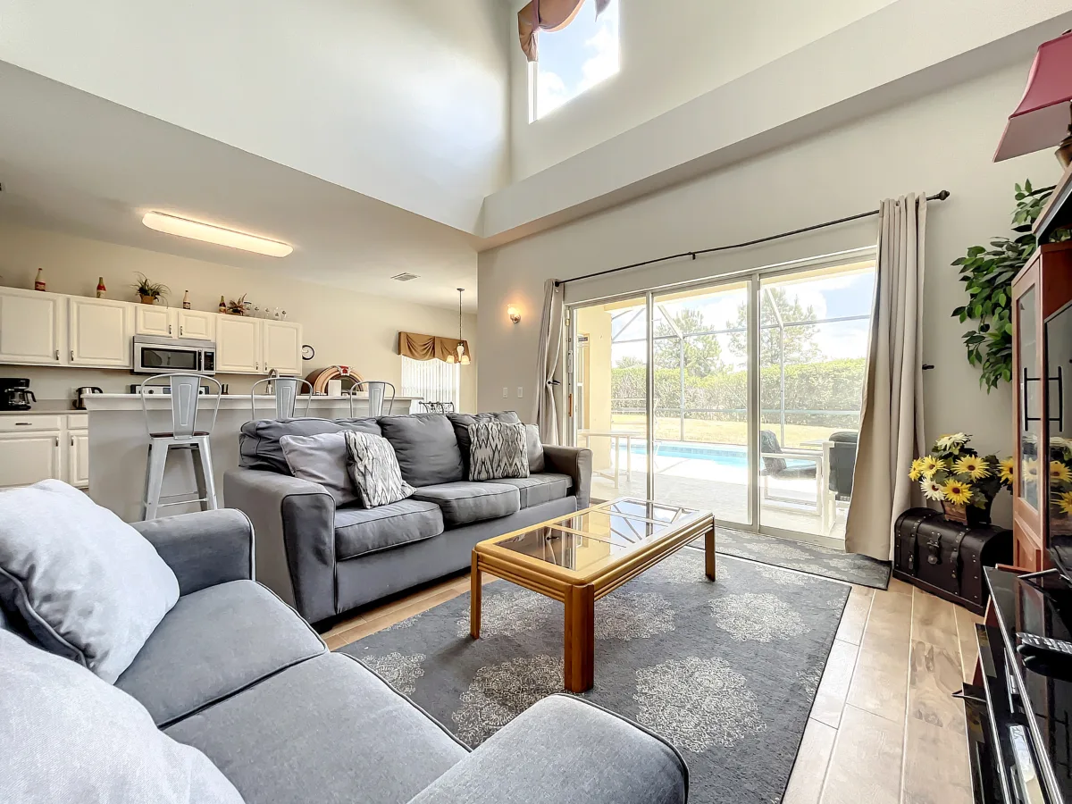 Open-plan living and kitchen with high ceilings looking out to the pool
